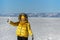 Happy woman wearing winter yellow jacket holding piece of transparent crushed ice cubes over her face