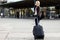 Happy Woman With Wheeled Luggage Walking Towards Train Station