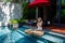 Happy woman in white swimsuit have floating breakfast in luxury pool at villa