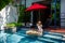 Happy woman in white swimsuit have floating breakfast in luxury pool at villa