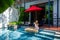 Happy woman in white swimsuit have floating breakfast in luxury pool at villa