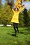 Happy woman in yellow coat jumping in autumn park