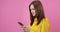 Happy woman in yellow raincoat texting message on smartphone