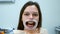 Happy woman with yellow teeth with retractor in her mouth is waiting dentist.