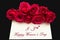 Happy Womans Day March 8th written on white card with red roses