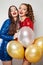 Happy women friends laughing. Fashion girls with balloons and sparkling wine glasses on white