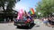 Happy women running with Gay Pride Car Parade handing out flowers to crowd