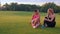 Happy women sitting on grass in summer park. DIverse friends talking outdoors