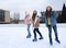 Happy women skating along ice rink outdoors