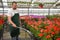 Happy worker growing flowers in a greenhouse of a flower shop