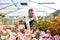 Happy worker growing flowers in a greenhouse of a flower shop