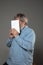 Happy world book day, read to become someone else - man covering face with book while reading on grey background