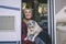 Happy young adult woman smile and enjoy best friends dogs sitting on the camper van door and looking outside. Travel lonely female