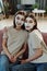 Happy young affectionate female twins with clay mask on faces sitting on couch