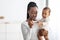 Happy young African American mother looking at thermometer