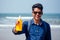 Happy young african man on the beach.India model male holding a bottle of sunscreen student teenager on vacation beach