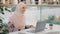 Happy young arab girl in hijab sitting at table answering video call on laptop joyfully waving hand greeting chatting