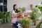 Happy young Asian beautiful woman wearing apron smiling and holding plant in wicker basket potted and take care of tree