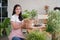 Happy young Asian beautiful woman wearing apron smiling and holding plant in wicker basket potted and take care of trees