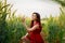 Happy young asian beautiful woman wearing red dress enjoying herself sitting and relax in the barley farm