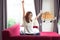 Happy young Asian business woman sitting on red sofa and stretching arm in her house in the morning. Business and Entrepreneur