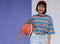 Happy young asian girl palying basketball with pastel background