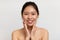 Happy young asian lady touching her cheeks and smiling at camera, korean woman enjoying skincare treatments