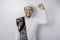 A happy young Asian Muslim man with a prayer rug on his shoulder showing a successful expression isolated by white background