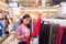 Happy young Asian woman checking a price tag on pants in mall or clothing store