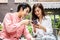 Happy Young asian woman sitting with boyfriend at cafe table, discussing over on smartphone, Young couple looking at mobile phone