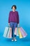 Happy young attractive short haired curly lady with casual hairstyle keeping a lot of paper bags in her hands while looking