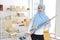 Happy young beautiful asian muslim housewife woman cleaning and playing vacuum cleaning like guitar with SME and E-commerce