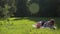 Happy young beautiful mother in glasses with her infant daughter lie on white blanket on green lawn