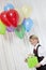 Happy young birthday boy with party balloon and gift looking away