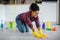 Happy young black housewife mopping floor with cleaning supplies, enjoy cleaning in kitchen interior