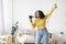 Happy young black lady with hair dryer as microphone singing and dancing at home, copy space