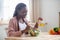 Happy young black lady preparing healthy vegetable salad in kitchen