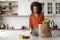 Happy Young Black Lady Unpacking Paper Bag With Groceries After Food Shopping