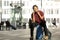 Happy young black travel man sitting on suitcase while talking on mobile phone in airport