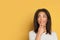 Happy young black woman thinking on yellow background