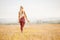 Happy young blonde girl holds water bottle in park, back frame