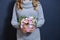 happy young blonde girl in a light gray sweater holds a bouquet of flowers in her hands on a dark gray background