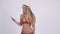 Happy young blonde tourist woman in bikini video calling with phone