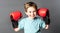 Happy young boy with freckles holding big boxing gloves