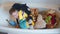 Happy young boy playing in a bath with soft toys.