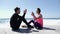 Happy young boyfriend and girlfriend playing high five clapping game sitting near the beach. Waves splashing against the rocks