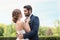 Happy young bride fixing bow tie of her groom outdoors