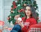 Happy young brunette female decorating christmas tree. Girl holding a christmas ball in her hands