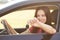 Happy young brunette female holds key while sits in luxury automobile, glad to recieve expensive present from relatives, focus on