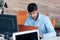 Happy young business man working on desktop computer at his desk in modern bright startup office interior